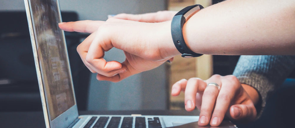 Two hands pointing at the monitor of a laptop