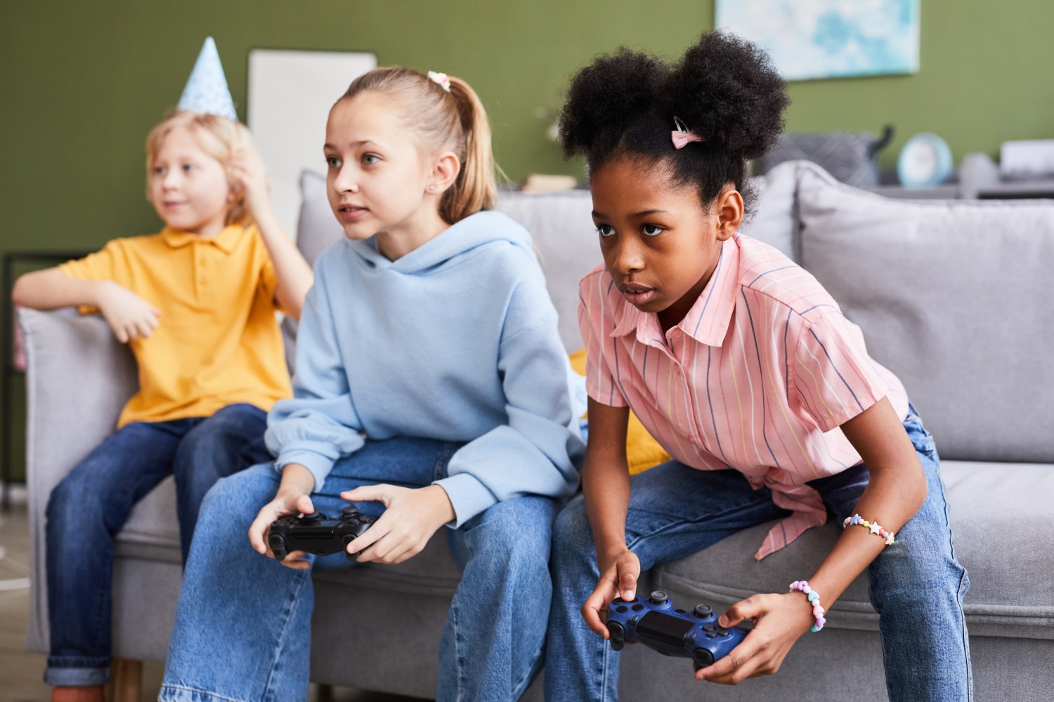 Three children in a living room play video games together.