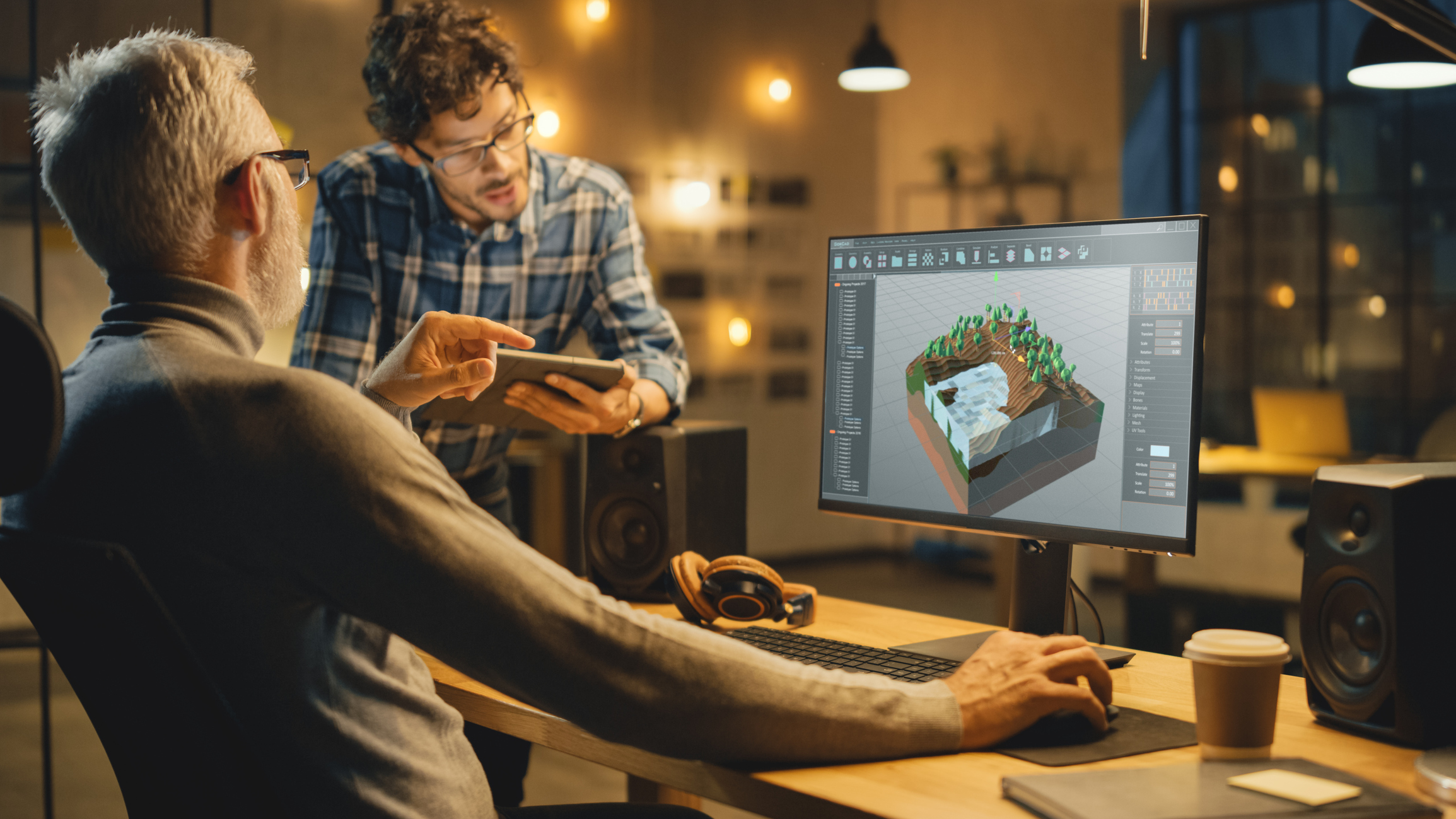 Two people working at a desktop computer to design a video game in a software design environment.