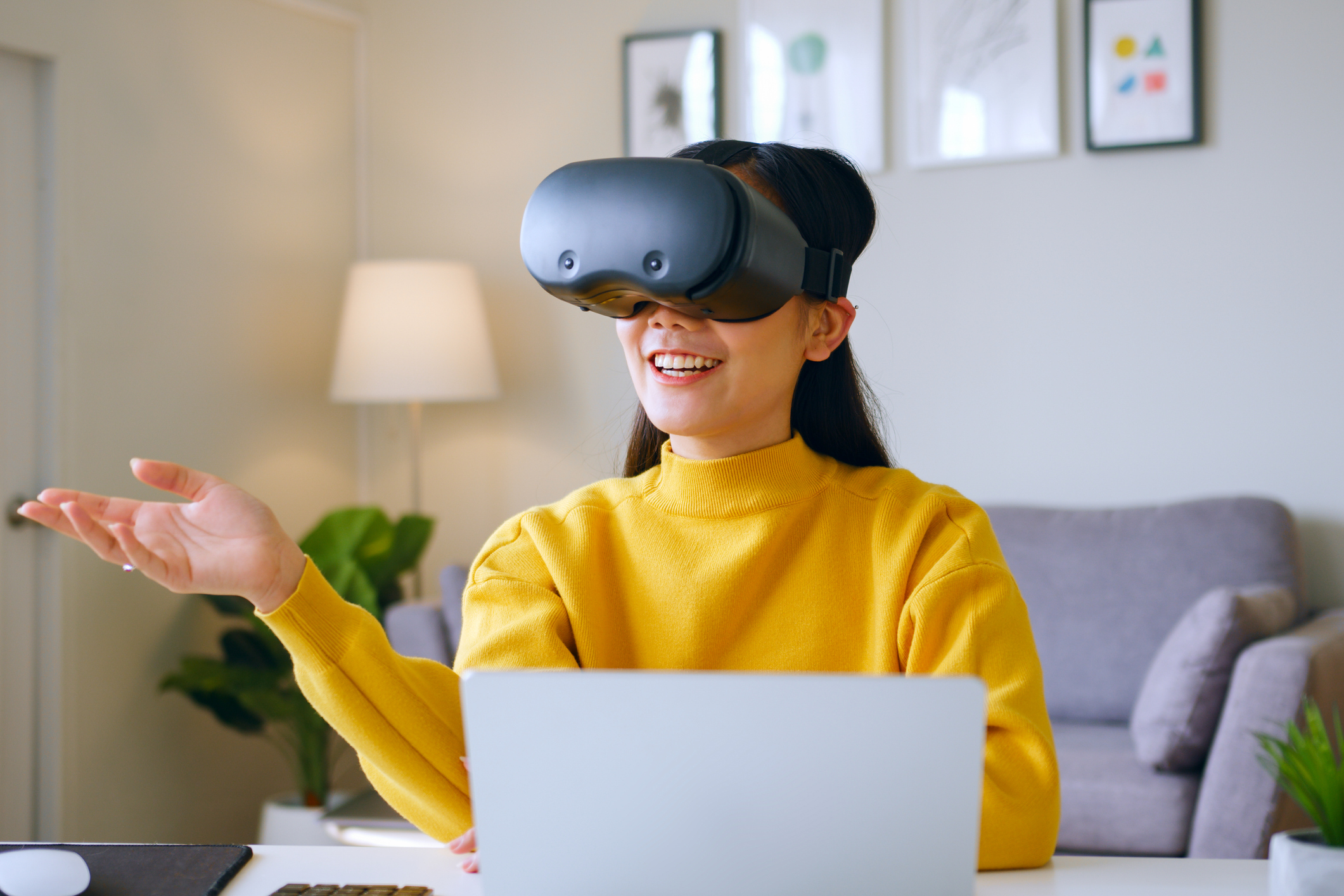 Young Asian woman talking while using 360 VR headset for online meeting in metaverse at home